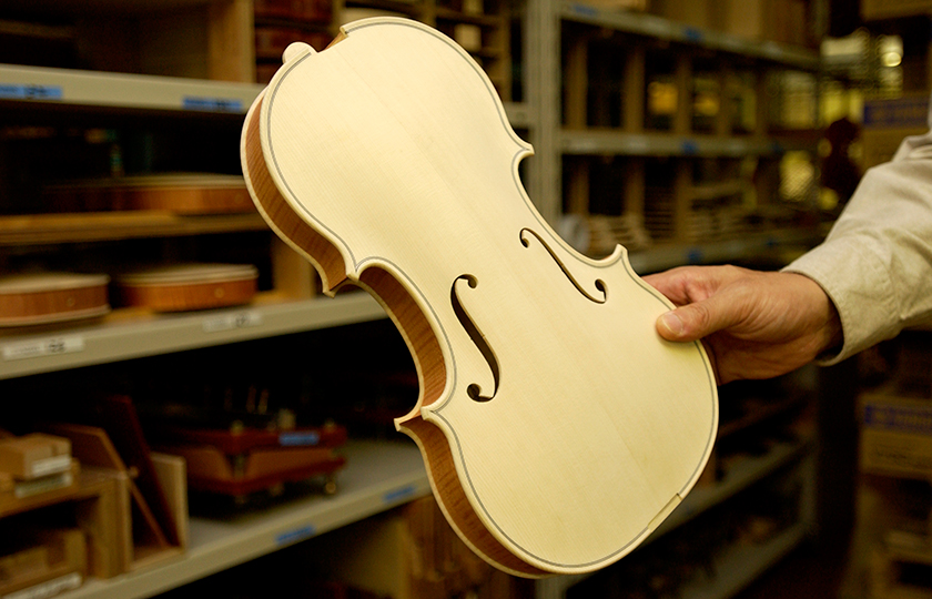 A white violin before the neck is attached