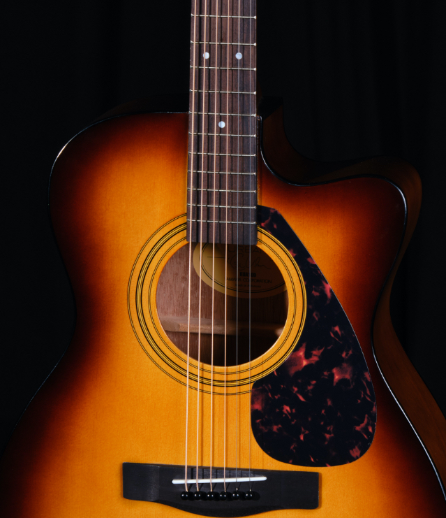 A person practicing guitar using the Urban App on their phone sitting on a coffee table.