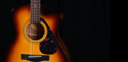 A person practicing guitar using the Urban App on their phone sitting on a coffee table.