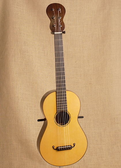 A fully restored nineteenth century guitar, showing the unique shape of the neck.