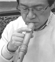 Photograph of blowing into the instrument while covering the windway with a finger. Modelled by Minoru Yoshizawa (recorder player)
