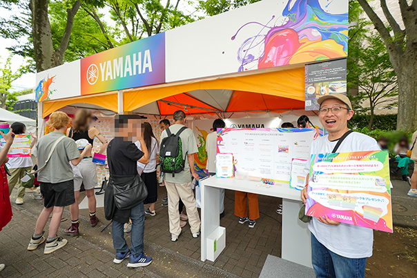 [ Image ] Volunteer employees at the Yamaha booth, instruments on display, and panels introducing the company's initiatives