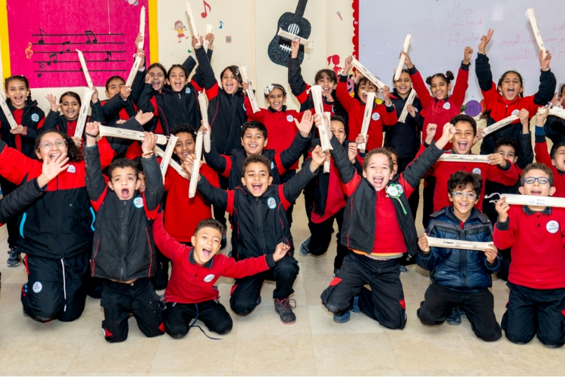[Image] Egyptian children holding recorders and posing with smiles in the classroom