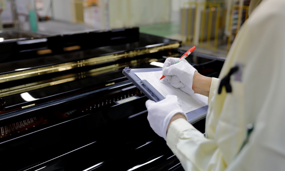 [Photo] Image of a Yamaha technician inspecting a piano key action test