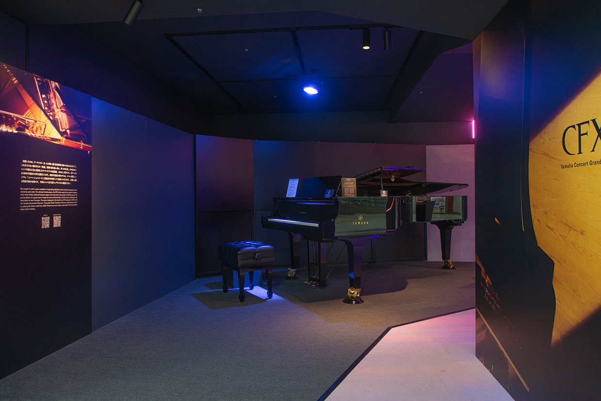 [ 画像 ] コンサートグランドピアノCFXの展示の様子。周りは黒を基調とした内装で、左右にCFXの特設パネルがある。
