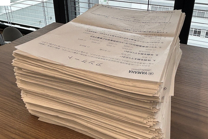 [写真] オフィスの窓際に置かれた大量の書類。1000件を優に超えた来場者アンケートの用紙。