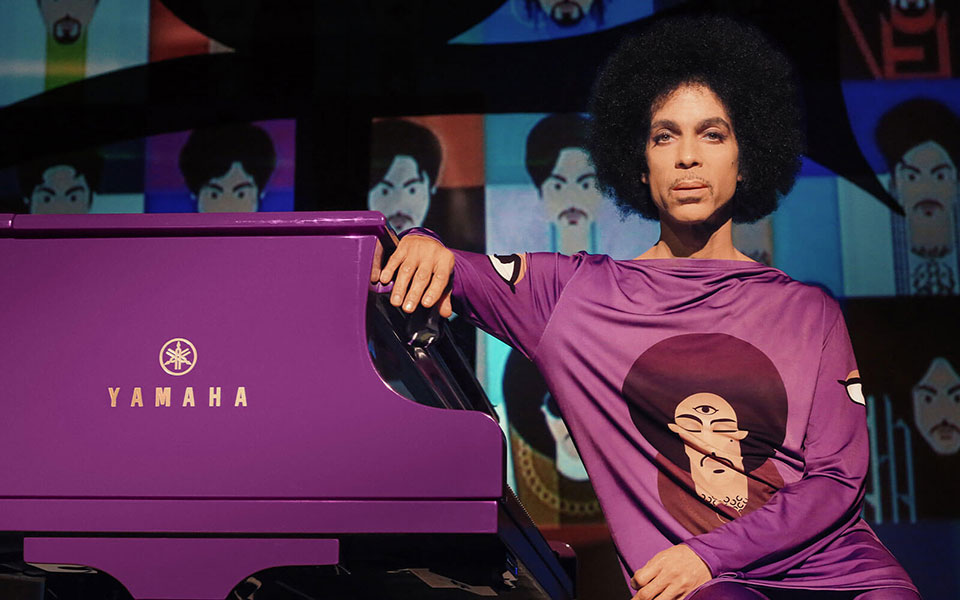 Prince sitting next to yamaha piano