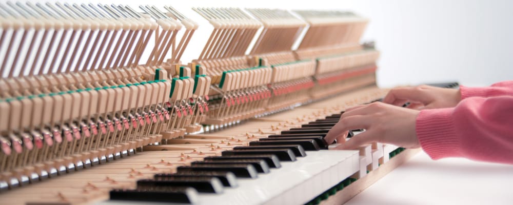 hands playing keyboard on an open piano 