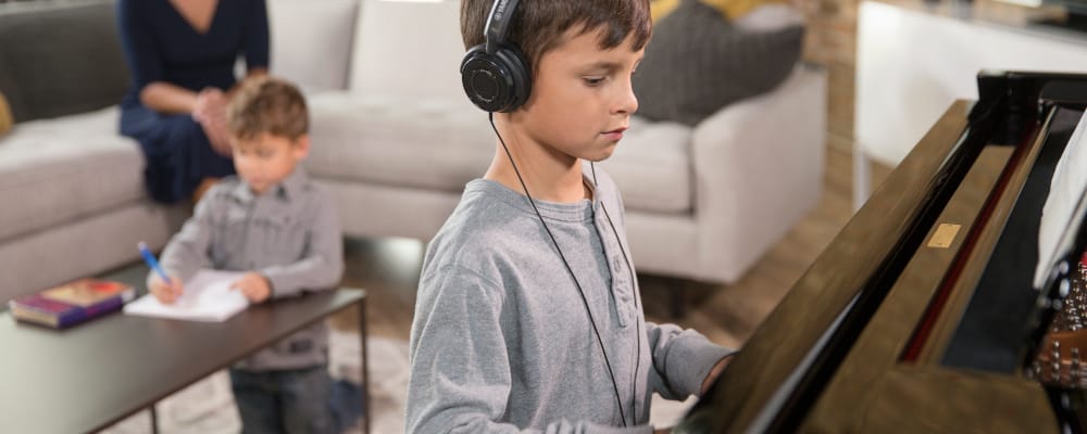 image of a young boy wearing a headphone and playing on a piano