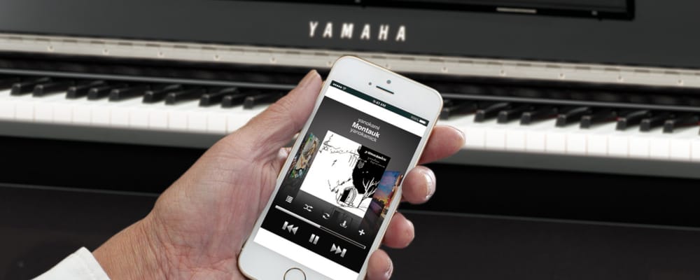 hand holding a mobile phone with a piano on a background