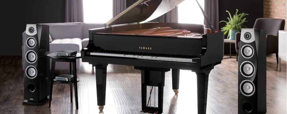 image of yamaha disklavier piano along with yamaha speaker in living room