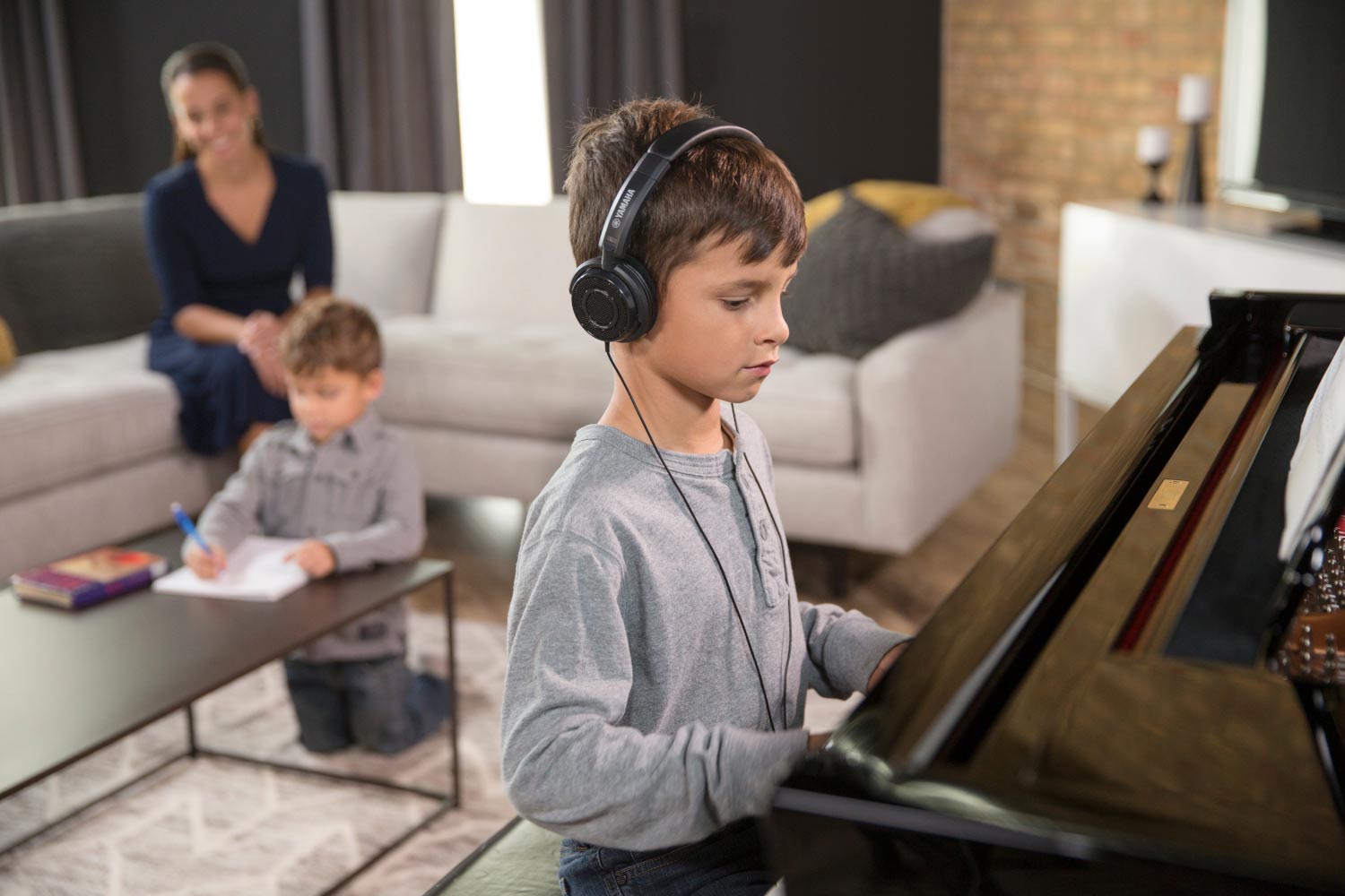 photo of a boy with headset playing Yamaha piano 
