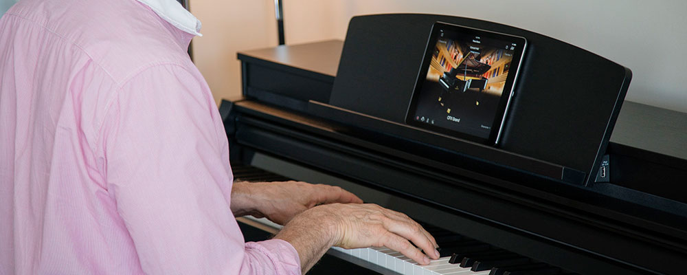 man playing clp piano with an ipad shwowing controls