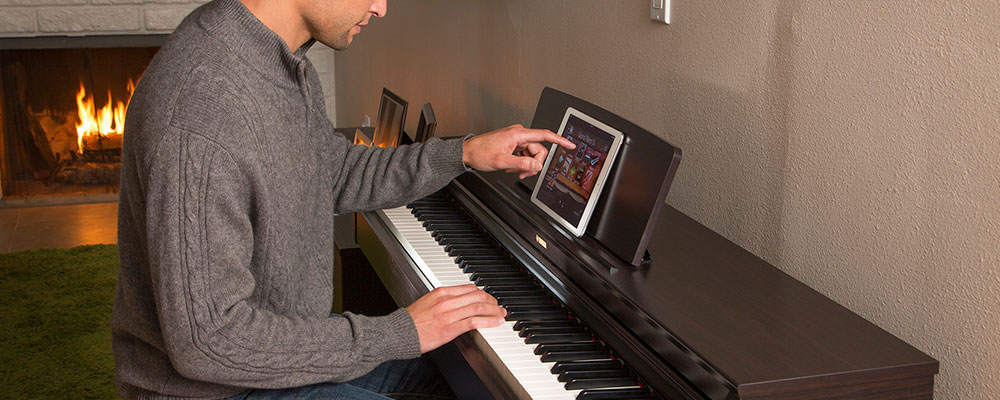 guy playing the piano in one hand and the other scrolling the ipad