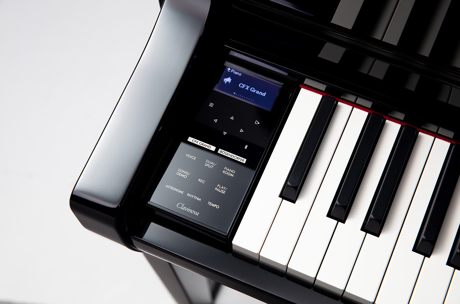 A view of a Yamaha grand piano's right side of the keyboard with lid open in background.