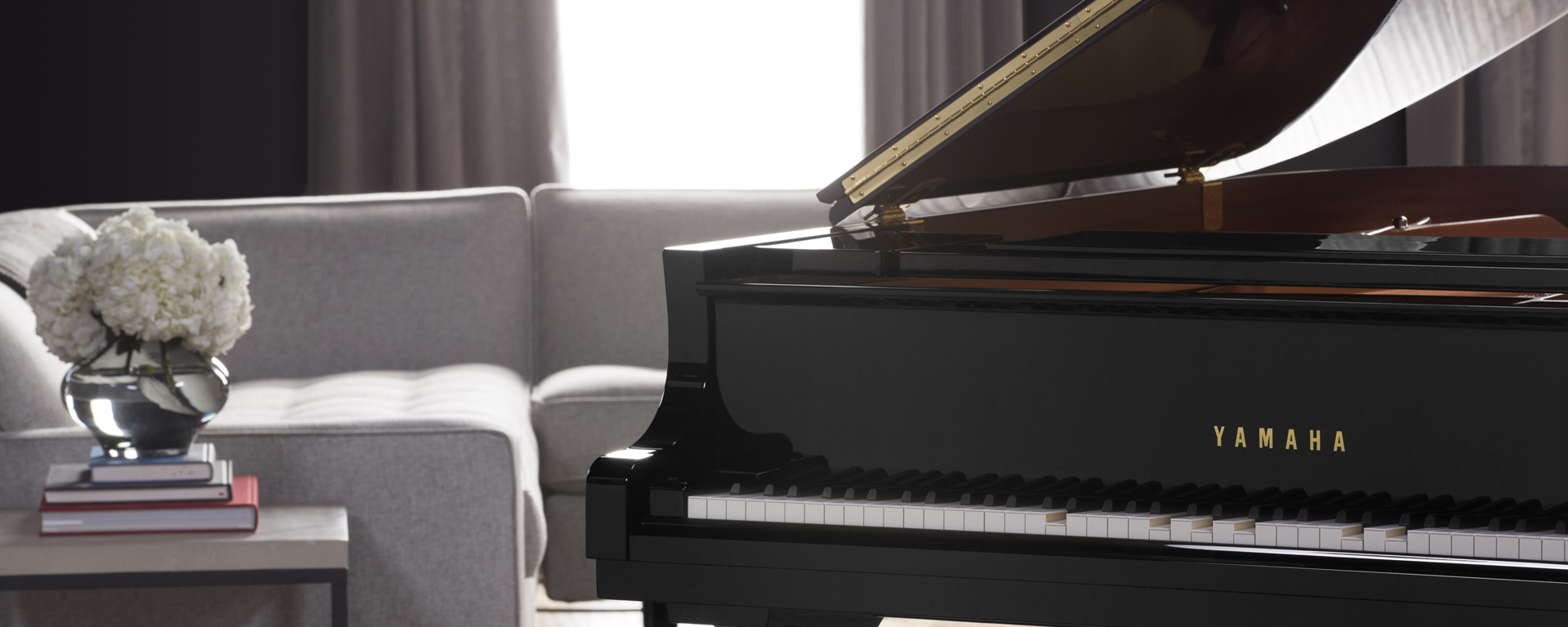 Man in his 20's dressed casually with curly hair and some facial hair playing a Yamaha piano.