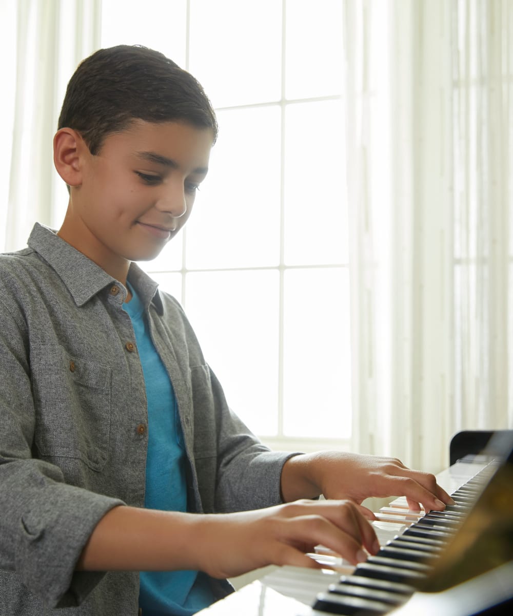 boy smiling while playing the upright piano