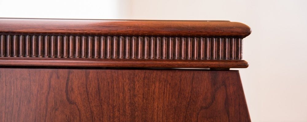 Closeup of the furniture type detailing of the wood case. This includes a border along top edge with a row of tiny posts.