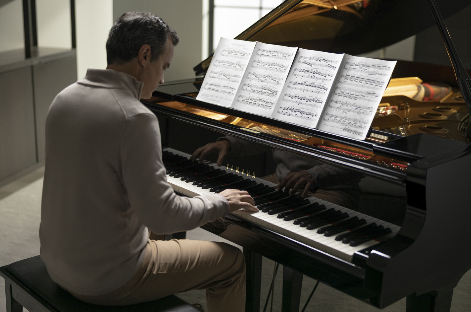 An older man in a suit playing a grand piano.