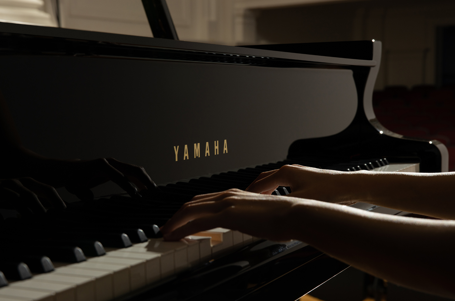 A view of a Yamaha grand piano's right side of the keyboard with lid open in background.