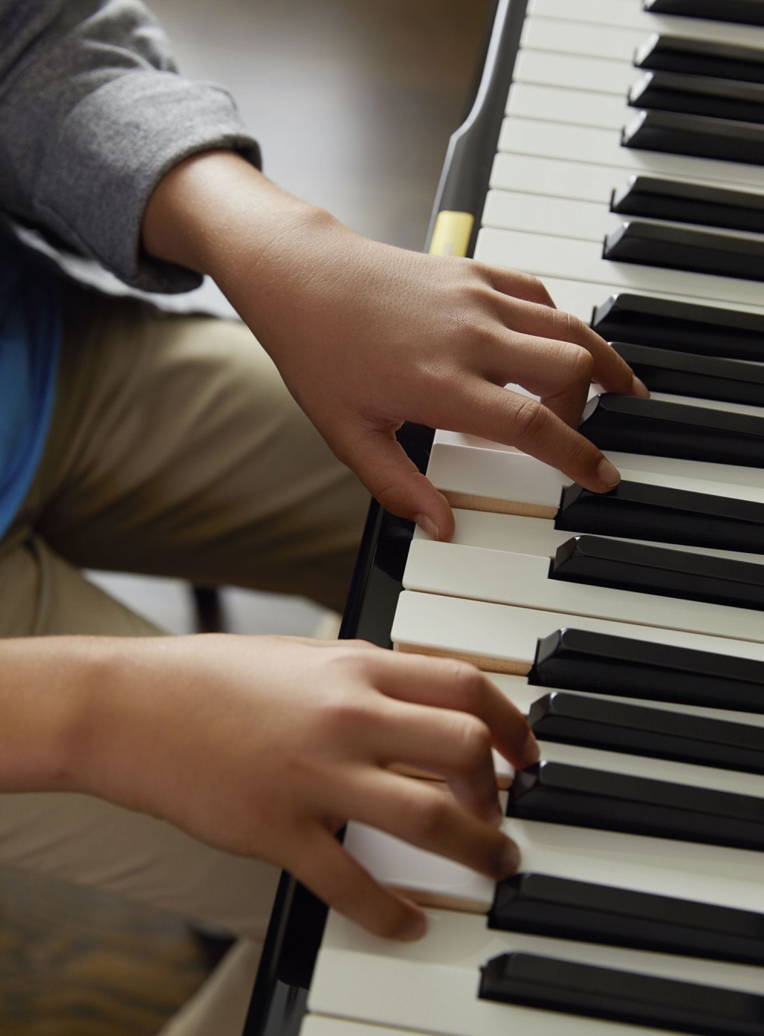 Young hands playing piano keys.