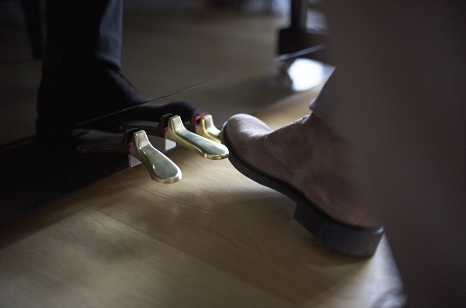 Closeup of booted foot using right hand pedal of the three pedals.