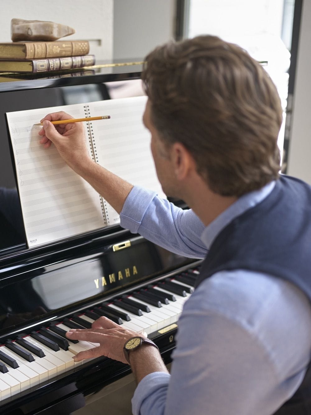 a man writing musical notes while one hand on the piano