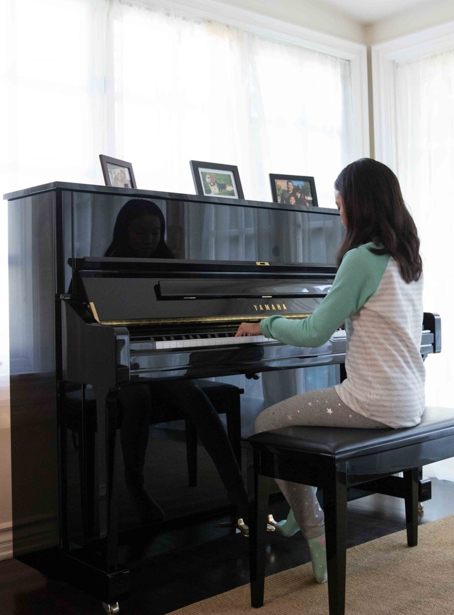 Young girl in her living room playing a Yamaha upright piano.