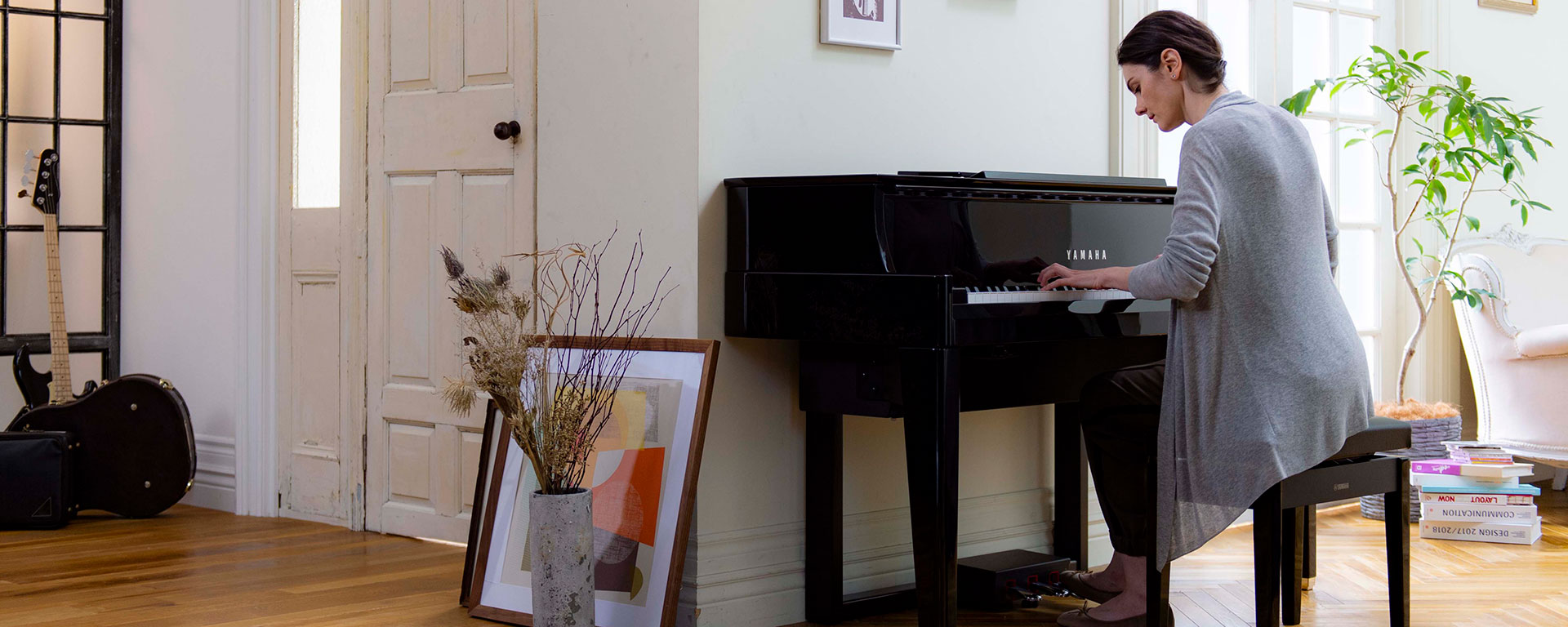 Man in his 20's dressed casually with curly hair and some facial hair playing a Yamaha piano.