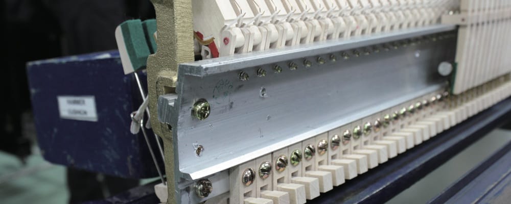 Closeup of the aluminum rail installed in a piano being built.