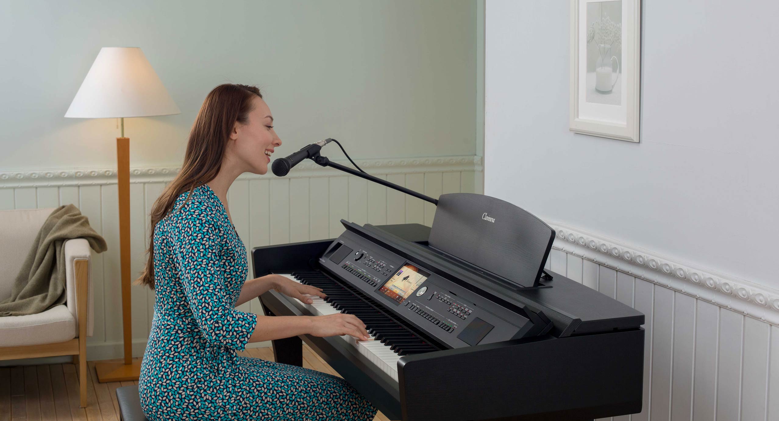 woman sitting singing on a microphone and playong CVP piano