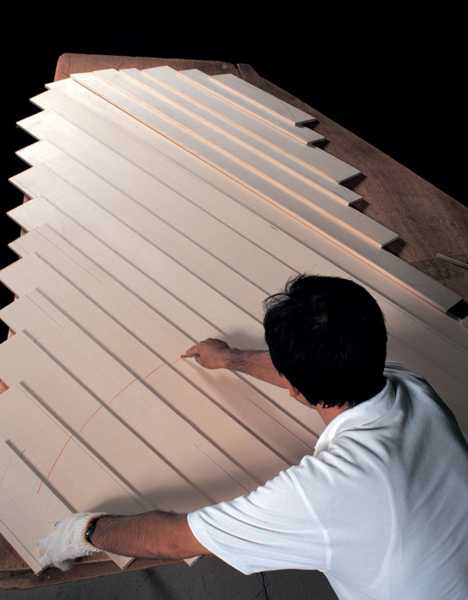 Craftsman drawing out the cutline on a set of overlapped, side by side wood boards.