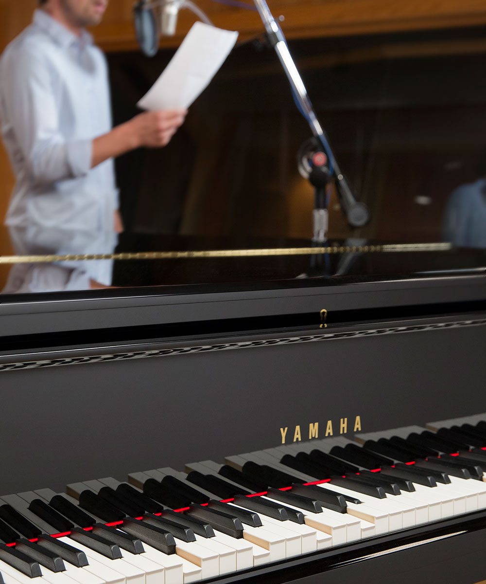 close-up view photo of Disklavier Piano and a person singing on a background