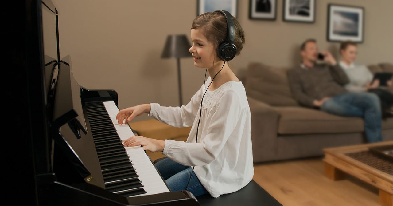 a young girl wearing a headset playing a hybrid piano