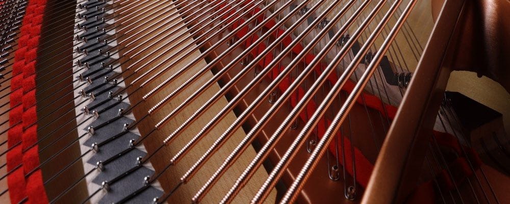 Closeup of bass strings in a finished piano showing that each of the strings are wrapped in another wire.