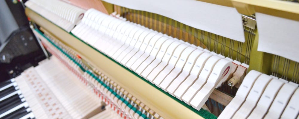 View of a row of hammers n process of being installed in an upright piano.